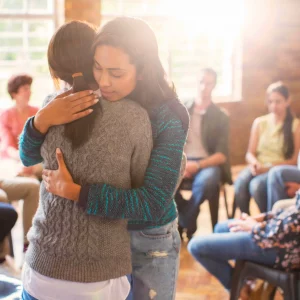 Dos mujeres abrazándose durante una dinámica práctica del Diploma en Constelaciones Familiares